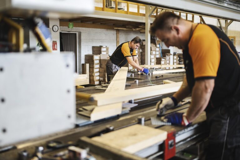 bildet viser menn som jobber med takstoler i en produksjonshall