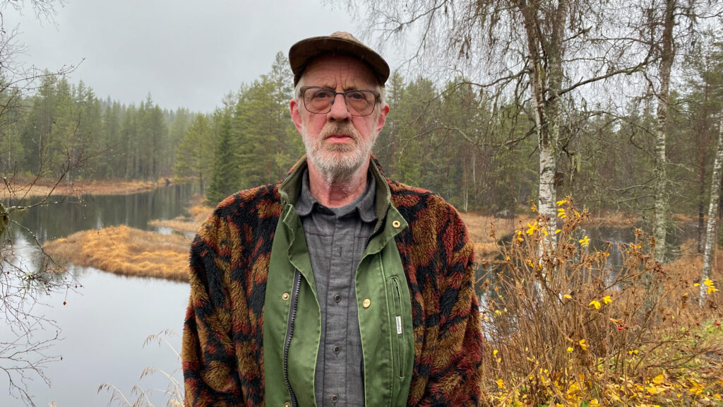Bildet viser Kjell Skaraberget i skogen foran et vann